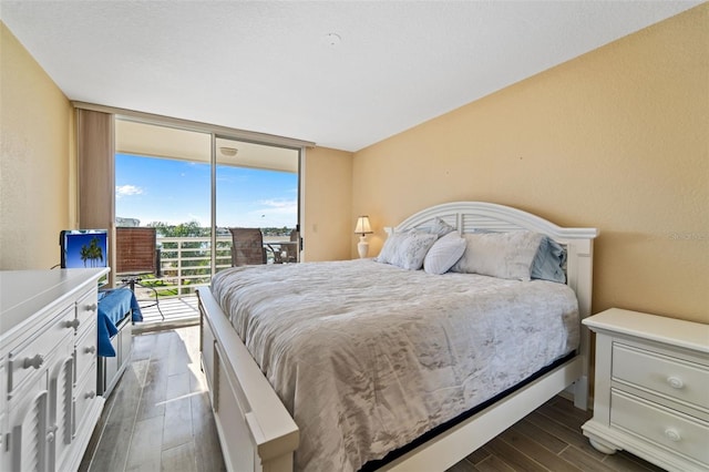 bedroom featuring access to outside, expansive windows, and dark wood-type flooring