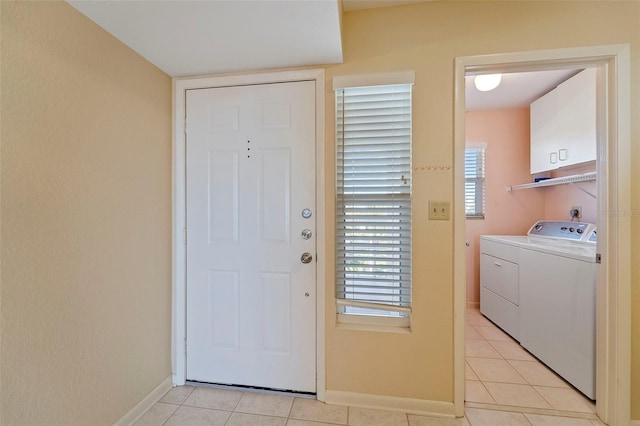 washroom featuring separate washer and dryer, light tile patterned flooring, and cabinets