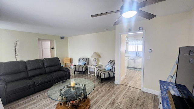 living room featuring light hardwood / wood-style floors, ceiling fan, and sink