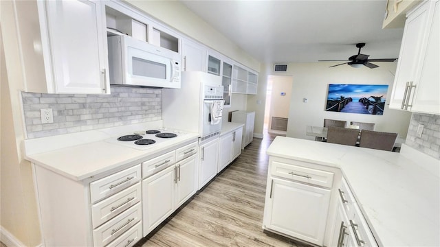 kitchen with tasteful backsplash, white cabinetry, and white appliances