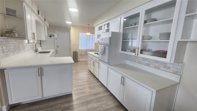 kitchen with white cabinetry, sink, backsplash, hardwood / wood-style floors, and decorative light fixtures