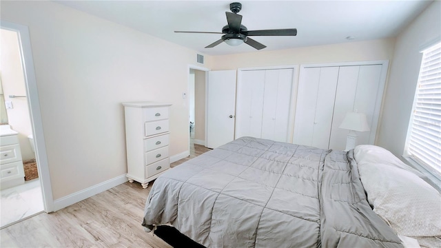 bedroom featuring connected bathroom, ceiling fan, light hardwood / wood-style floors, and two closets