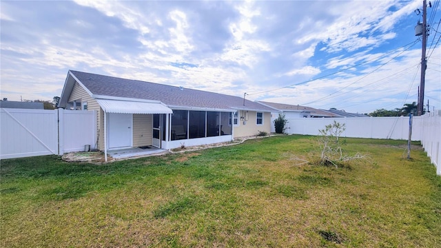 rear view of house featuring a sunroom and a lawn