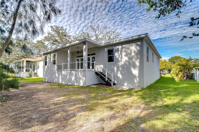 back of property featuring a lawn and ceiling fan