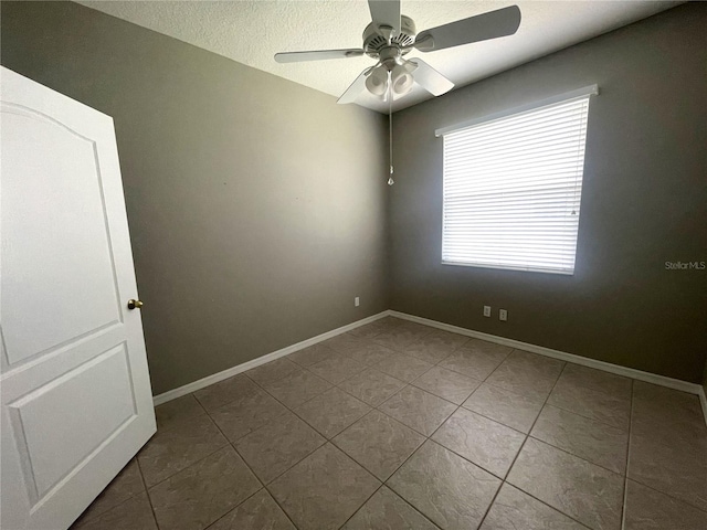 tiled empty room featuring a textured ceiling and ceiling fan