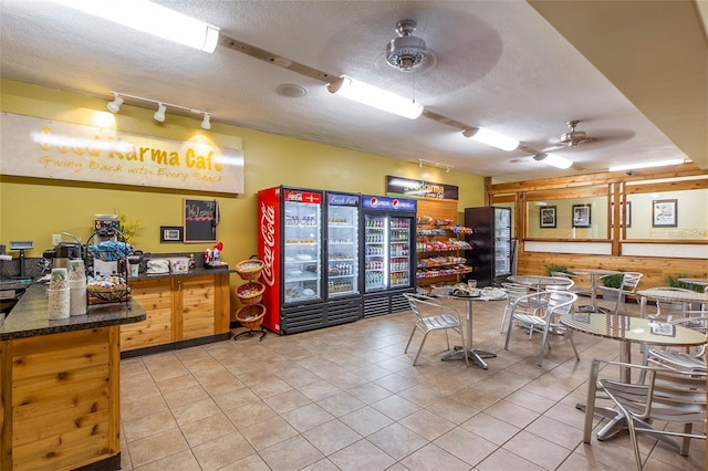 interior space featuring wood walls, ceiling fan, light tile patterned flooring, and a textured ceiling