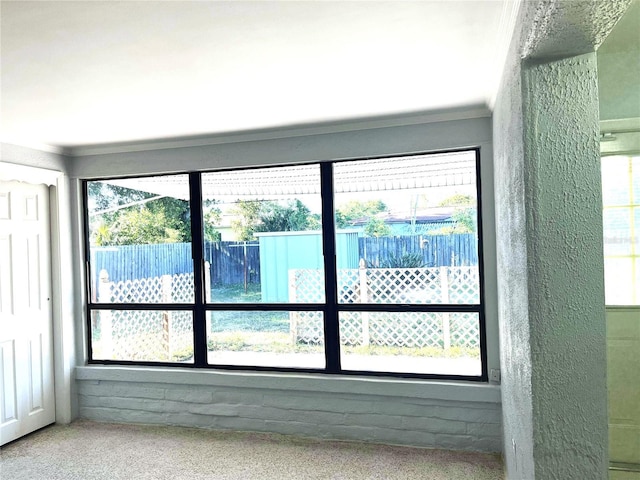 doorway to outside with carpet, crown molding, and a healthy amount of sunlight