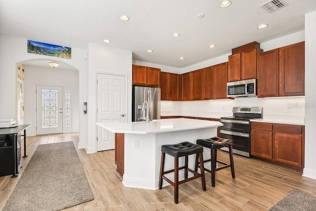 kitchen featuring a kitchen bar, stainless steel appliances, and a kitchen island with sink