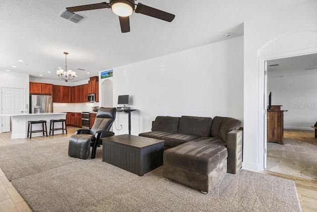 living room with light hardwood / wood-style floors and ceiling fan with notable chandelier