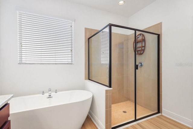 bathroom featuring plus walk in shower, hardwood / wood-style floors, and vanity