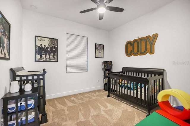 bedroom featuring carpet flooring, ceiling fan, and a nursery area