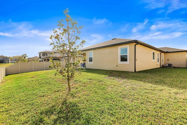 rear view of property with central AC and a yard