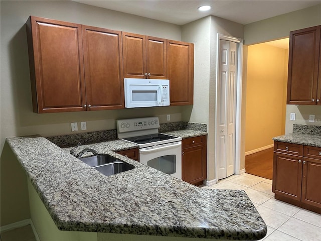 kitchen featuring sink, light tile patterned flooring, dark stone counters, and white appliances