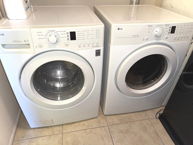 washroom featuring washer and clothes dryer and light tile patterned flooring