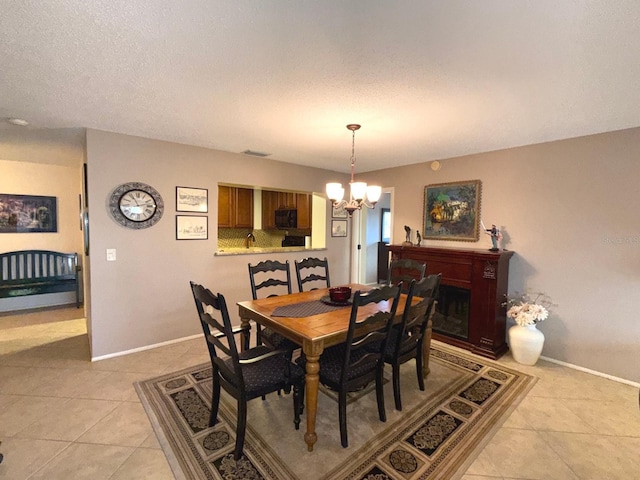 dining area with a notable chandelier, light tile patterned floors, and a textured ceiling