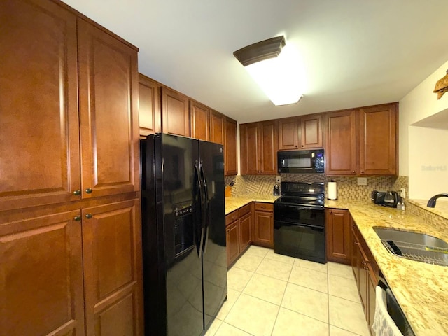 kitchen with light stone countertops, sink, tasteful backsplash, light tile patterned floors, and black appliances