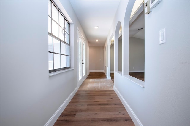 corridor featuring a barn door, dark hardwood / wood-style flooring, and lofted ceiling