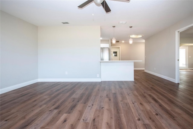 unfurnished living room with dark hardwood / wood-style flooring and ceiling fan