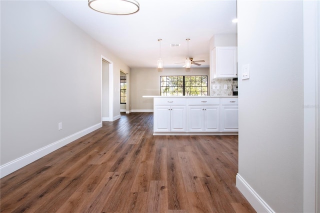 kitchen featuring white cabinetry, dark hardwood / wood-style flooring, backsplash, kitchen peninsula, and decorative light fixtures