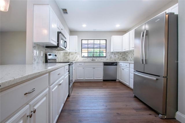 kitchen with white cabinetry, sink, light stone countertops, dark hardwood / wood-style floors, and appliances with stainless steel finishes