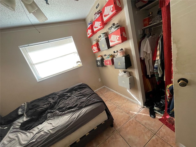 tiled bedroom with ceiling fan, a closet, and a textured ceiling