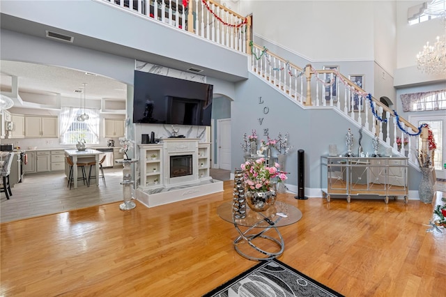 living room with an inviting chandelier, a towering ceiling, and light wood-type flooring