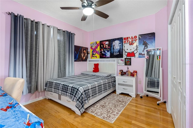 bedroom with ceiling fan, hardwood / wood-style flooring, and a textured ceiling