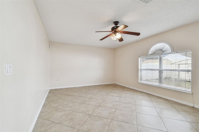 spare room featuring ceiling fan, light tile patterned floors, and a textured ceiling