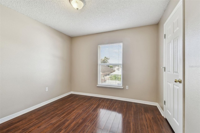 empty room featuring a textured ceiling and dark hardwood / wood-style floors