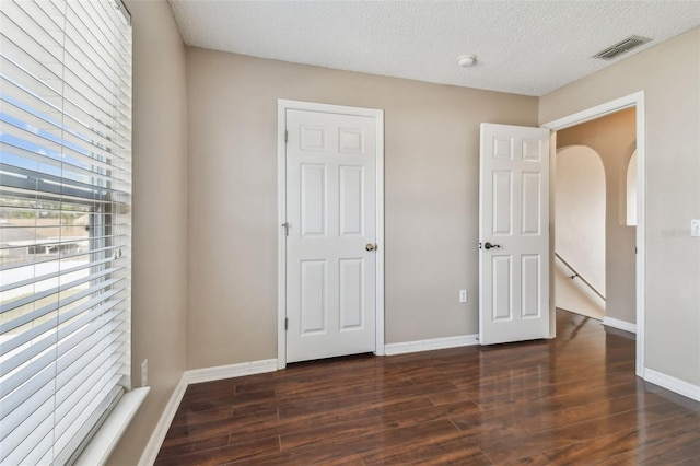 6213 Venezia Pl, Riverview, FL 33578 - unfurnished bedroom with dark wood-style floors, a textured ceiling, and arched walkways