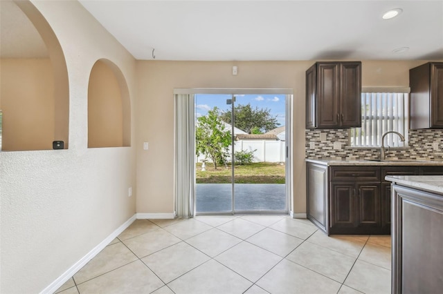 6213 Venezia Pl, Riverview, FL 33578 - kitchen featuring backsplash, dark brown cabinets, light tile patterned floors, recessed lighting, and light stone counters