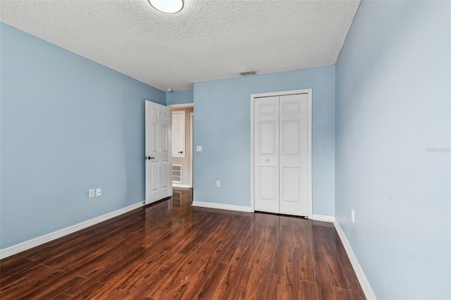 unfurnished bedroom featuring dark hardwood / wood-style flooring, a textured ceiling, and a closet