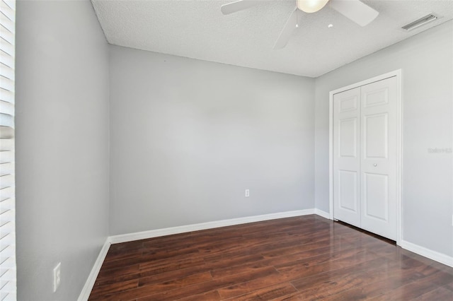 unfurnished bedroom with dark hardwood / wood-style flooring, ceiling fan, a closet, and a textured ceiling