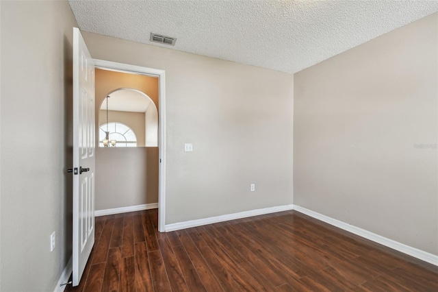 unfurnished room with dark hardwood / wood-style flooring and a textured ceiling