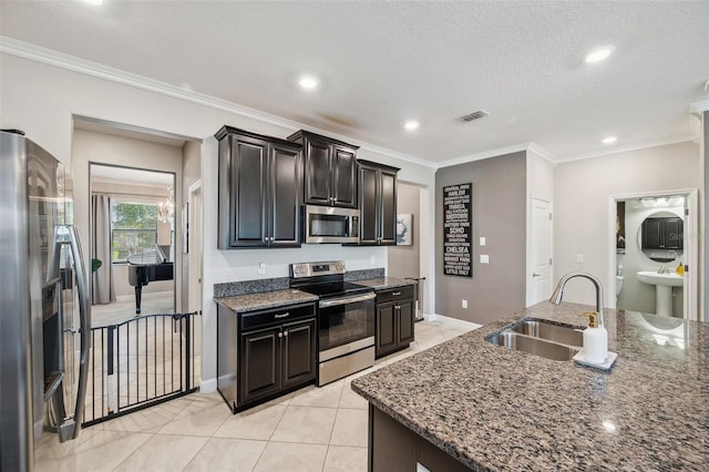 kitchen with sink, crown molding, dark stone counters, light tile patterned floors, and appliances with stainless steel finishes