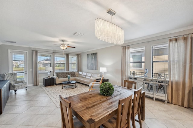 tiled dining space with ceiling fan, ornamental molding, and a textured ceiling