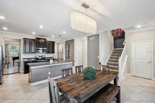 dining area featuring light tile patterned flooring, ornamental molding, sink, and an inviting chandelier