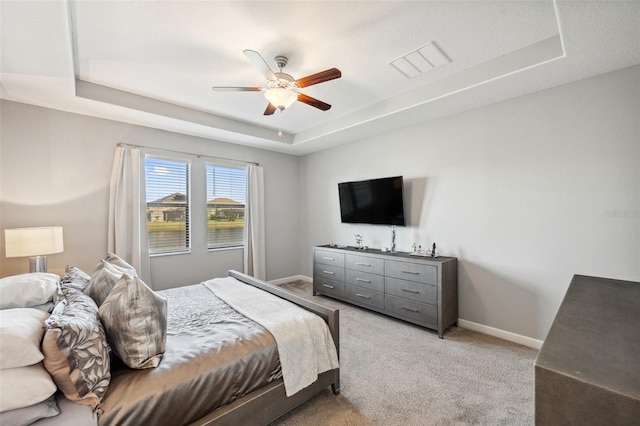 carpeted bedroom featuring ceiling fan and a raised ceiling