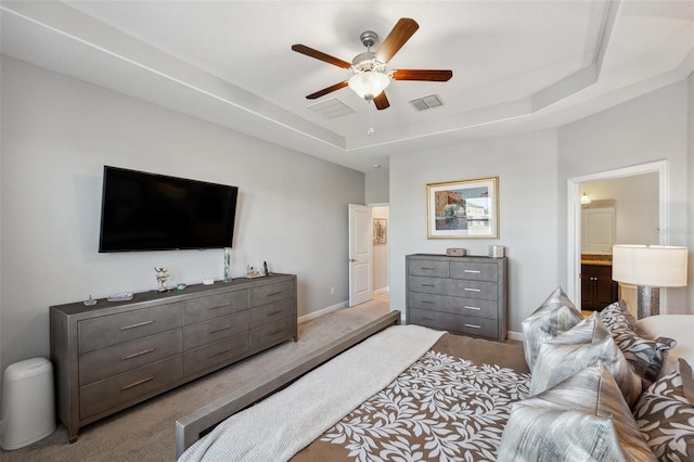 carpeted bedroom with ensuite bathroom, a raised ceiling, and ceiling fan