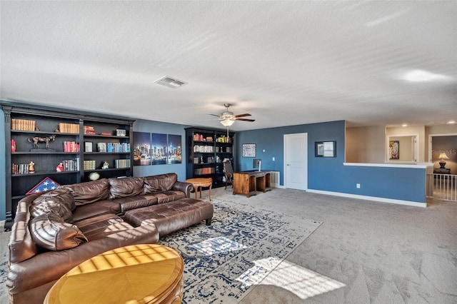 living room featuring ceiling fan, carpet floors, and a textured ceiling