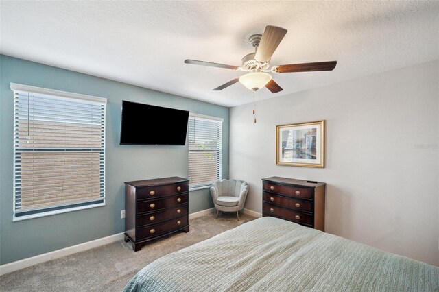 carpeted bedroom featuring ceiling fan and a textured ceiling