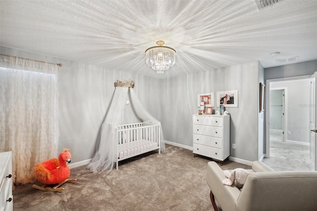 bedroom featuring a chandelier, carpet, a nursery area, and a textured ceiling