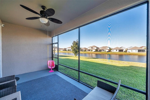 unfurnished sunroom with ceiling fan, a water view, and heating unit