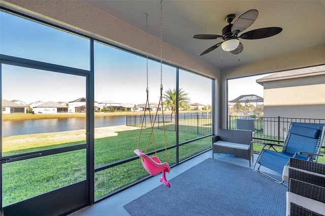 sunroom / solarium featuring a water view and ceiling fan