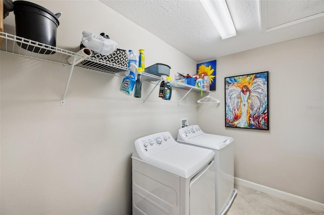 clothes washing area with washing machine and dryer and a textured ceiling