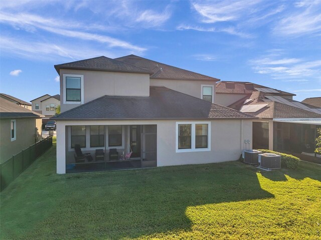 back of property with a lawn, central air condition unit, and a sunroom