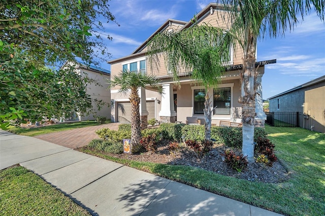 view of front of house featuring covered porch, a garage, and a front lawn