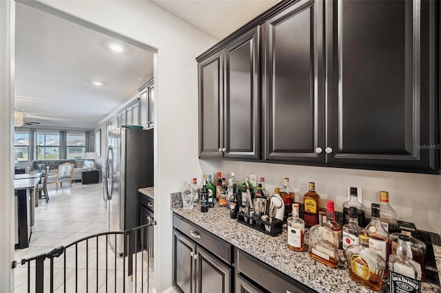 kitchen featuring stainless steel refrigerator, light stone counters, and light tile patterned floors