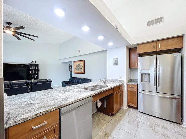 kitchen featuring kitchen peninsula, light stone counters, stainless steel appliances, ceiling fan, and sink