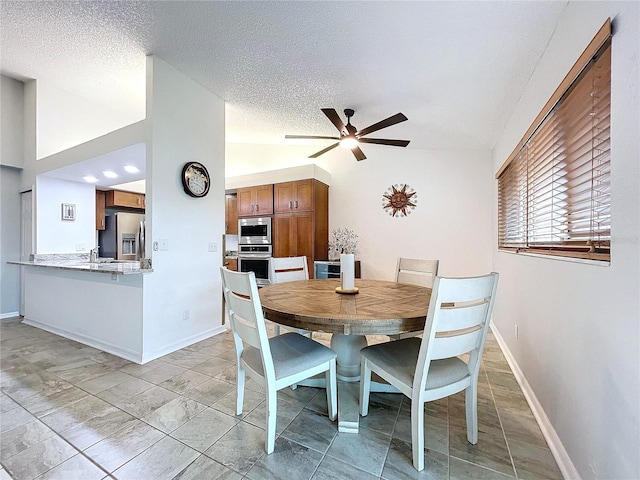 dining room with ceiling fan, lofted ceiling, a textured ceiling, and light tile patterned floors